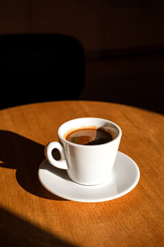 A cup of black coffee on the table in the sunlight