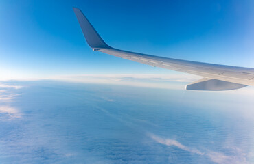View from the airplane window at a beautiful cloudy sky and the airplane wing