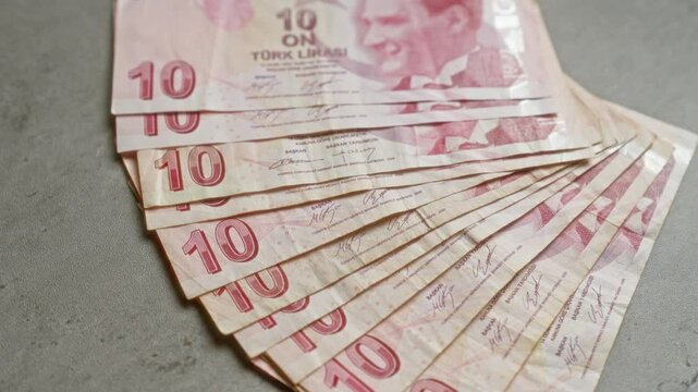 Turkish lira banknotes spread out on a concrete surface, showcasing the currency denomination and a portrait of a historical figure from turkey.