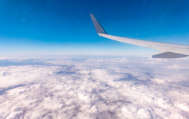 View from the airplane window at a beautiful cloudy sky and the airplane wing