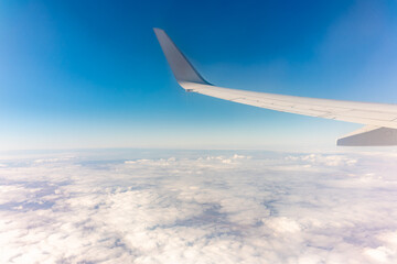 View from the airplane window at a beautiful cloudy sky and the airplane wing