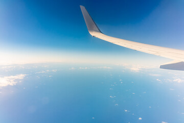 View from the airplane window at a beautiful blue clear sky and the airplane wing