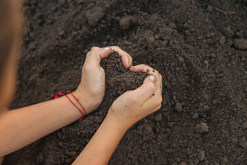 Child holding soil and plant in hands. Selective focus.