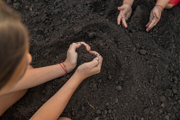 Child holding soil and plant in hands. Selective focus.