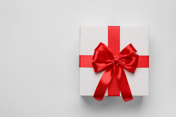 Gift box with red bow on light grey background, top view. Space for text
