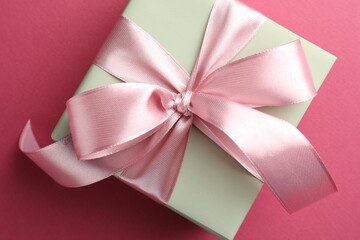 Beautiful gift box with bow on pink background, top view