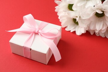 Gift box with bow and flowers on red background