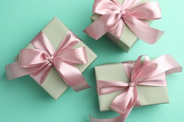 Gift boxes with bows on turquoise background, flat lay