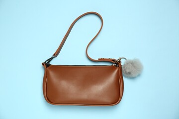 Bag with grey faux fur keychain on light blue background, top view