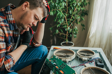 Electrician trying to understand why a modern induction hob is not working, holding a circuit board...