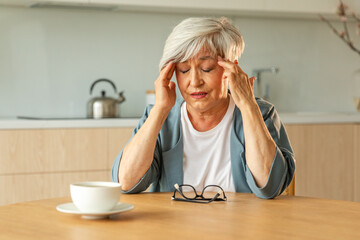Headache pain. Unhappy middle aged senior woman suffering from headache sick rubbing temples at...