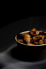 Fried chicken in a cardboard container on a black background in the shade with smoke