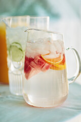 Jug, fruit water and home for healthy beverage, nutrition and table setup for celebration. Drink, glass and decoration and special event for festive arrangement, holiday catering and detox liquid