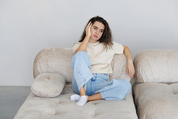 Stressed young woman suffering migraine and complaining sitting on a couch at home