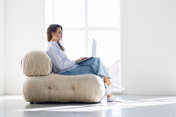 Young woman sitting cross-legged using laptop at home