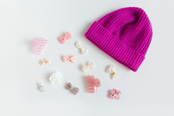 Pink knitted hat and hair accessories on a white background. Girls accessories flat lay. Fashion, shopping, capsule wardrobe concept.
