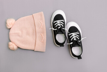 Kids clothing. Knitted hat with cneakers on the grey background. Top view. Fashion concept. Child girl's autumn clothes