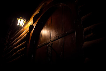 Spooky dark view of an old street lantern lighting on top of a wooden cabin door