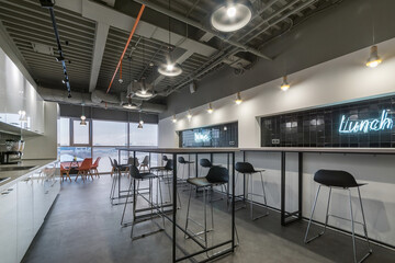 Office coffee shop with a white kitchen set. Bar stools and tables. A snack place.