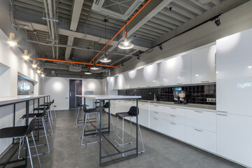 A snack room in an office building. White kitchen set with special equipment. High tables and...