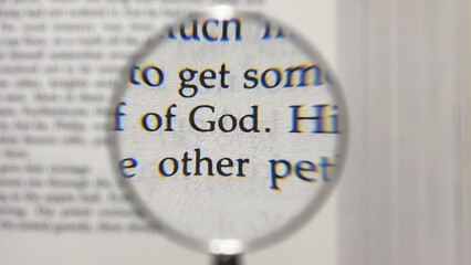 Photo of the word God magnified by a magnifying glass in a book written in English