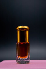 Bottle of perfume or oil on a dark background. Mockup of a perfume bottle standing on a pink pedestal