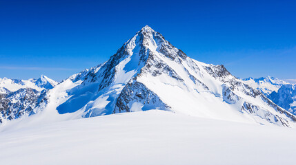 Stunning snow-covered mountain peak under a bright blue sky, showcasing the beauty of pristine alpine landscapes.
