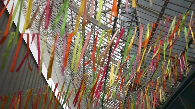 Colorful decorations in the wind in a cozy yard. Hanging multi-colored ribbons for a summer holiday. Yellow and blue ribbons sway in the wind. High quality FullHD footage