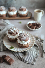 Double Chocolate Cream Puffs on a plate. Stripped grey napkin and pieces of chocolate. Grey background.