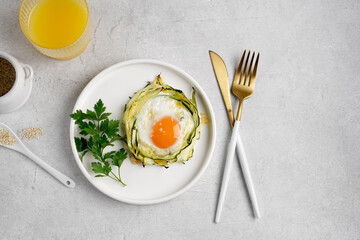 fried egg in zucchini noodle nest with sesame and juice in glass, healthy breakfast, top view, copy space