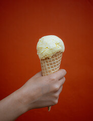 Hand holding organic ice cream cone on red textured background