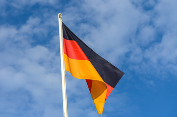 The German flag waving proudly against a clear blue sky on a sunny day