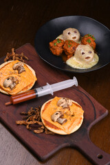 halloween idea funny and horrifying dishes two mini pizza with skull and mushroom with sauce in a syringe dumpling ghost meat in angle view