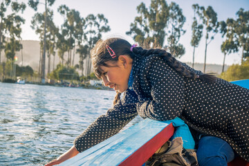 latin girl playing in a boat taking a ride on lake achocalla in bolivia - concept of playing