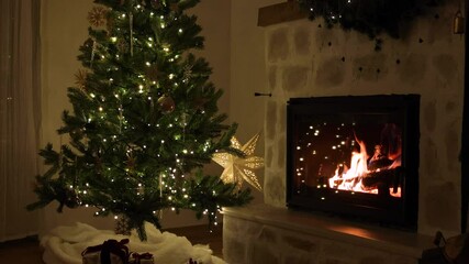 Merry Christmas! Stylish decorated christmas tree with vintage ornaments, wrapped presents and cozy burning fireplace with decor in evening. Atmospheric christmas eve at home, holiday footage