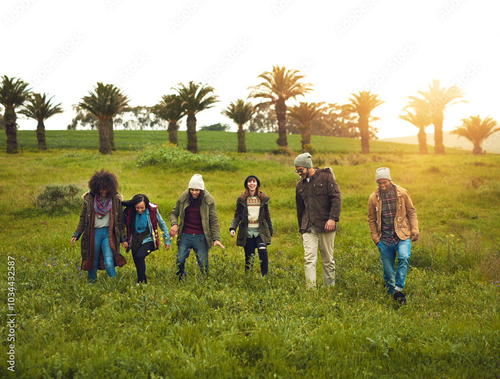 Wall mural Walking, field and friends with nature, travel and getaway trip with adventure, countryside and lens flare. Outdoor, people and group with grass, journey and bonding together with happiness or joyful