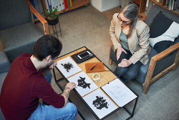 Therapy, psychologist and man with inkblot test for personality assessment or support above....