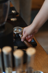 person placing a portafilter on a coffee scale for a barista course