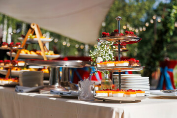 An elegant dessert table at a wedding reception, adorned with an assortment of cakes, cupcakes, and cookies