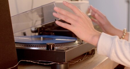 An individual is currently engaged in playing a vinyl record on a turntable, enjoying the rich sound produced by the spinning disc