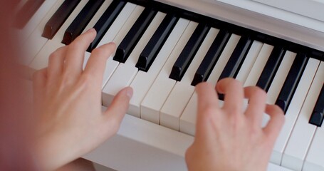 A person is skillfully playing a piano with their hands gracefully positioned on the keys, producing beautiful music as they go