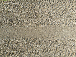 A close-up view of a textured surface showing tire tracks and gravel, perfect for backgrounds and abstract art