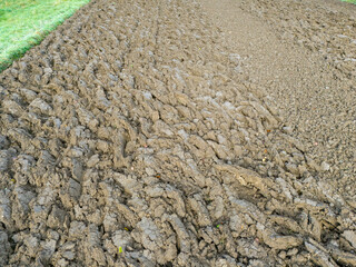 A close-up view of freshly plowed farmland, showcasing textured soil patterns in a rural setting, ideal for agriculture-related projects.