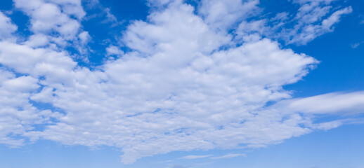 A vast blue sky filled with fluffy white clouds, creating a serene and calming atmosphere. Perfect for backgrounds or nature-themed projects.