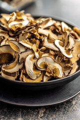 Dried porcini mushrooms. Sliced boletus on plate on black table.