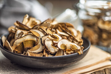 Dried porcini mushrooms. Sliced boletus on plate on wooden table.