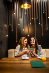 Two girl best friends having out at the restaurant. Drinking coffee and orange juice. They gossip, laugh and have fun time.