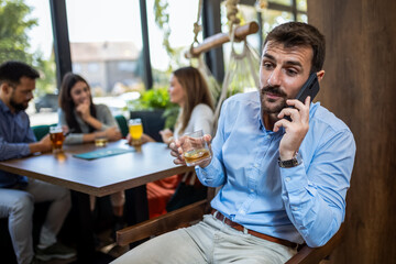 Businessman drinking whisky and talking on the phone.