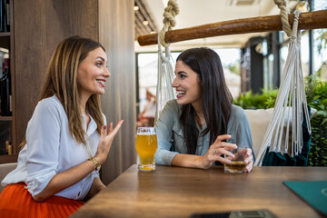 Two girl best friends having out at the restaurant. Drinking coffee and orange juice. They gossip, laugh and have fun time.