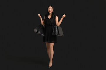 Beautiful happy woman with shopping bags on dark background. Black Friday Sale